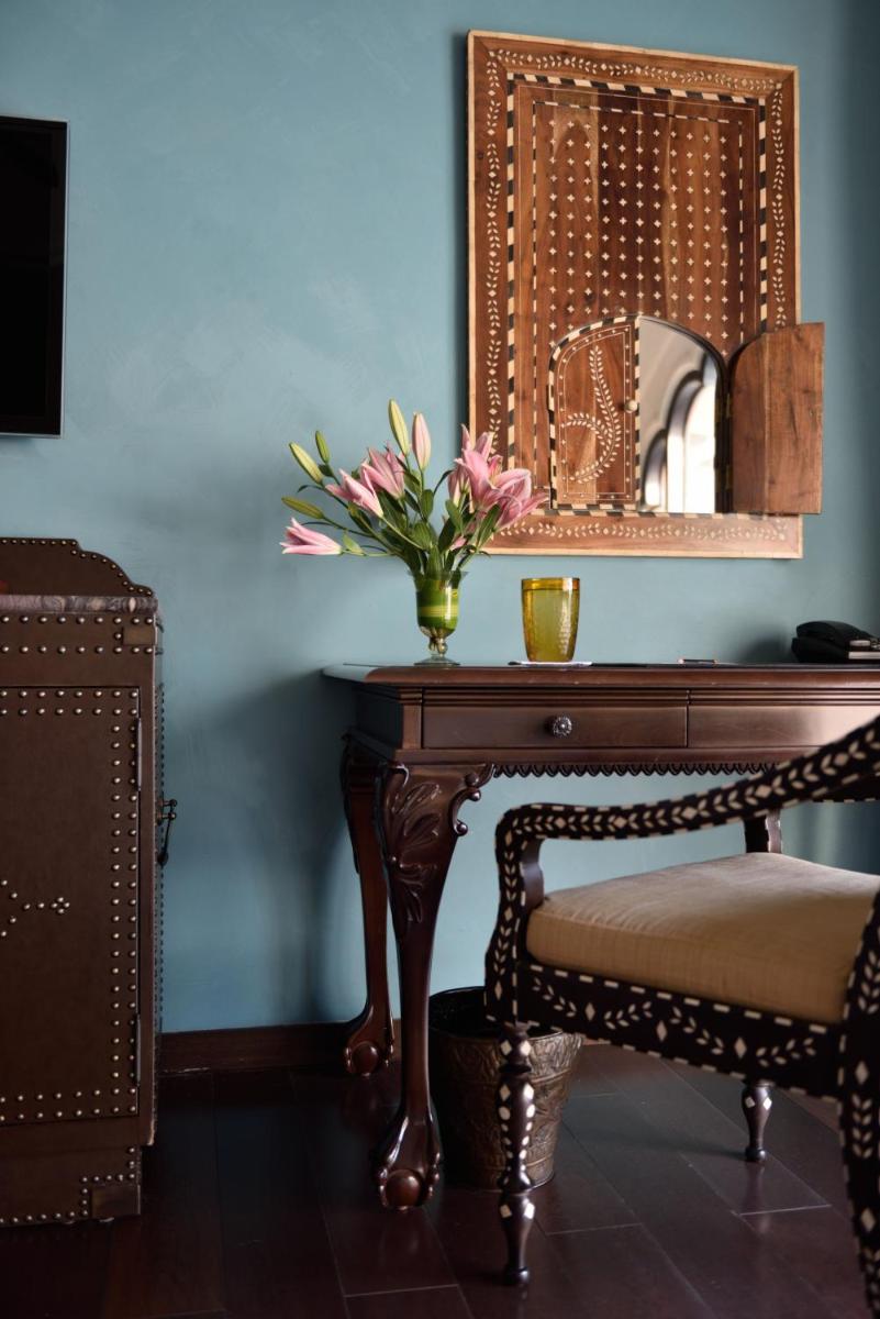 a table with a vase of flowers and a mirror at Fairmont Jaipur in Jaipur