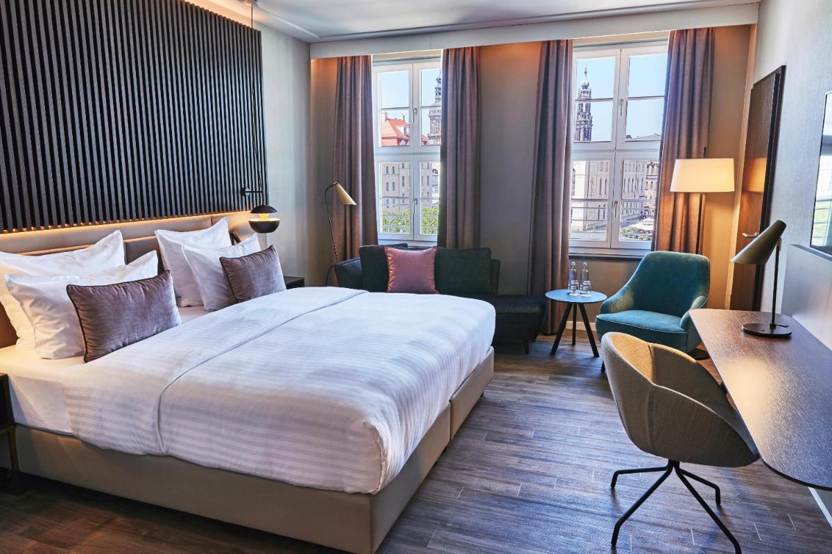 ein Hotelzimmer mit einem Bett, einem Schreibtisch und Stühlen in der Unterkunft Steigenberger Hotel de Saxe in Dresden ein Hotelzimmer mit einem Bett, einem Schreibtisch und Stühlen in der Unterkunft Steigenberger Hotel de Saxe in Dresden