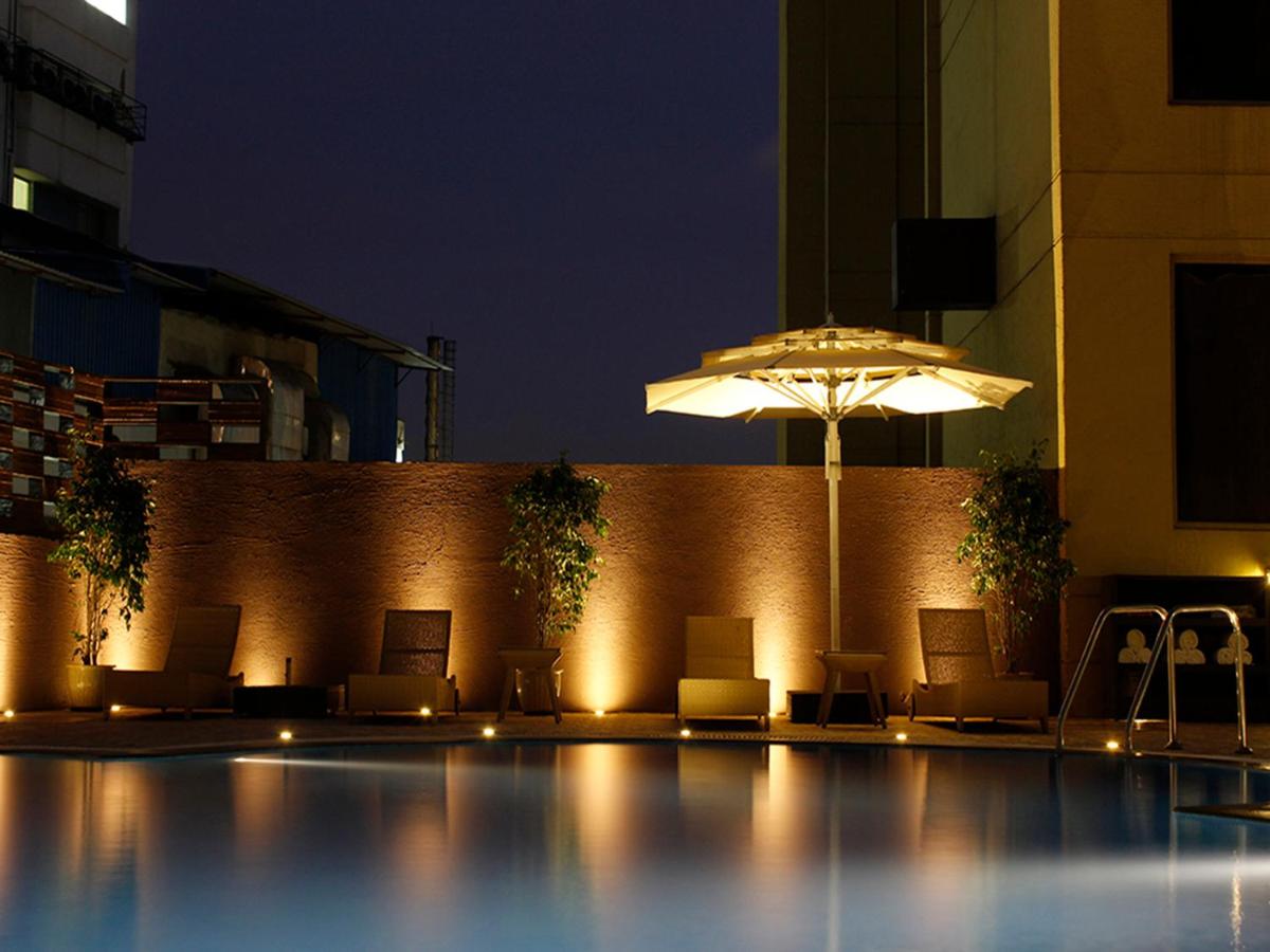 a pool with chairs and an umbrella at night at Sterlings Mac Hotel in Bengaluru