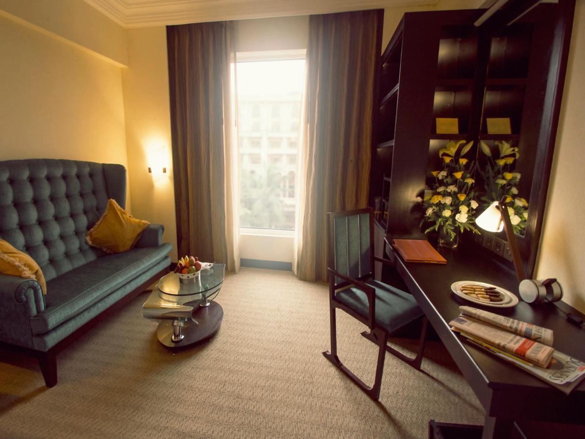 a living room with a blue couch and a table at Sterlings Mac Hotel in Bengaluru
