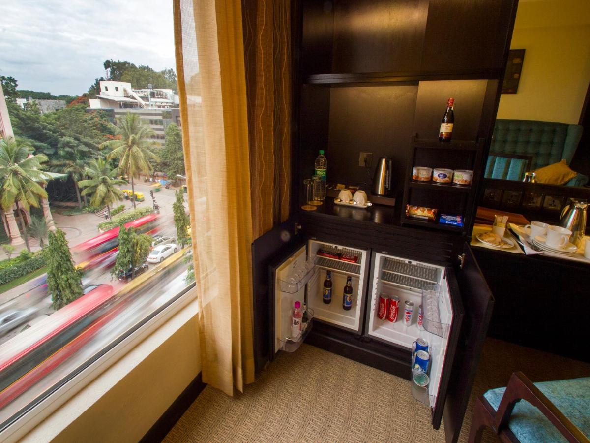 a small refrigerator in a room with a window at Sterlings Mac Hotel in Bengaluru