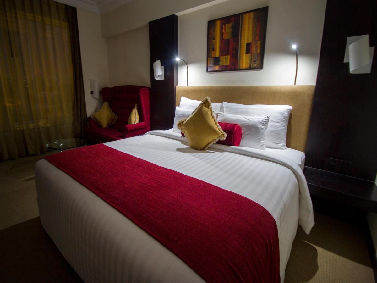 a bedroom with a large bed with a red and white blanket at Sterlings Mac Hotel in Bengaluru