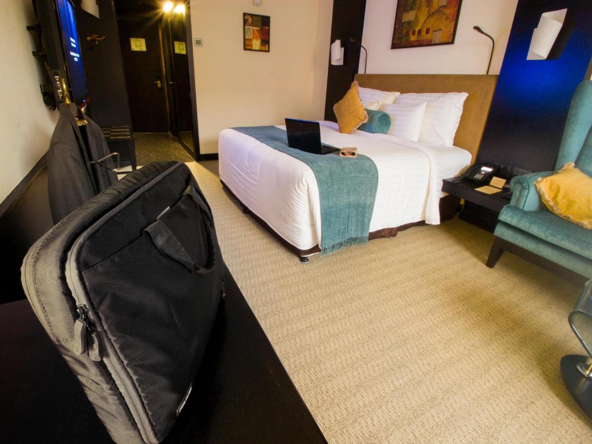 a hotel room with a bed and a suitcase at Sterlings Mac Hotel in Bengaluru