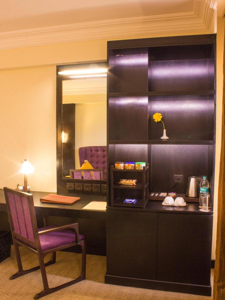 a room with a desk and a chair and a mirror at Sterlings Mac Hotel in Bengaluru