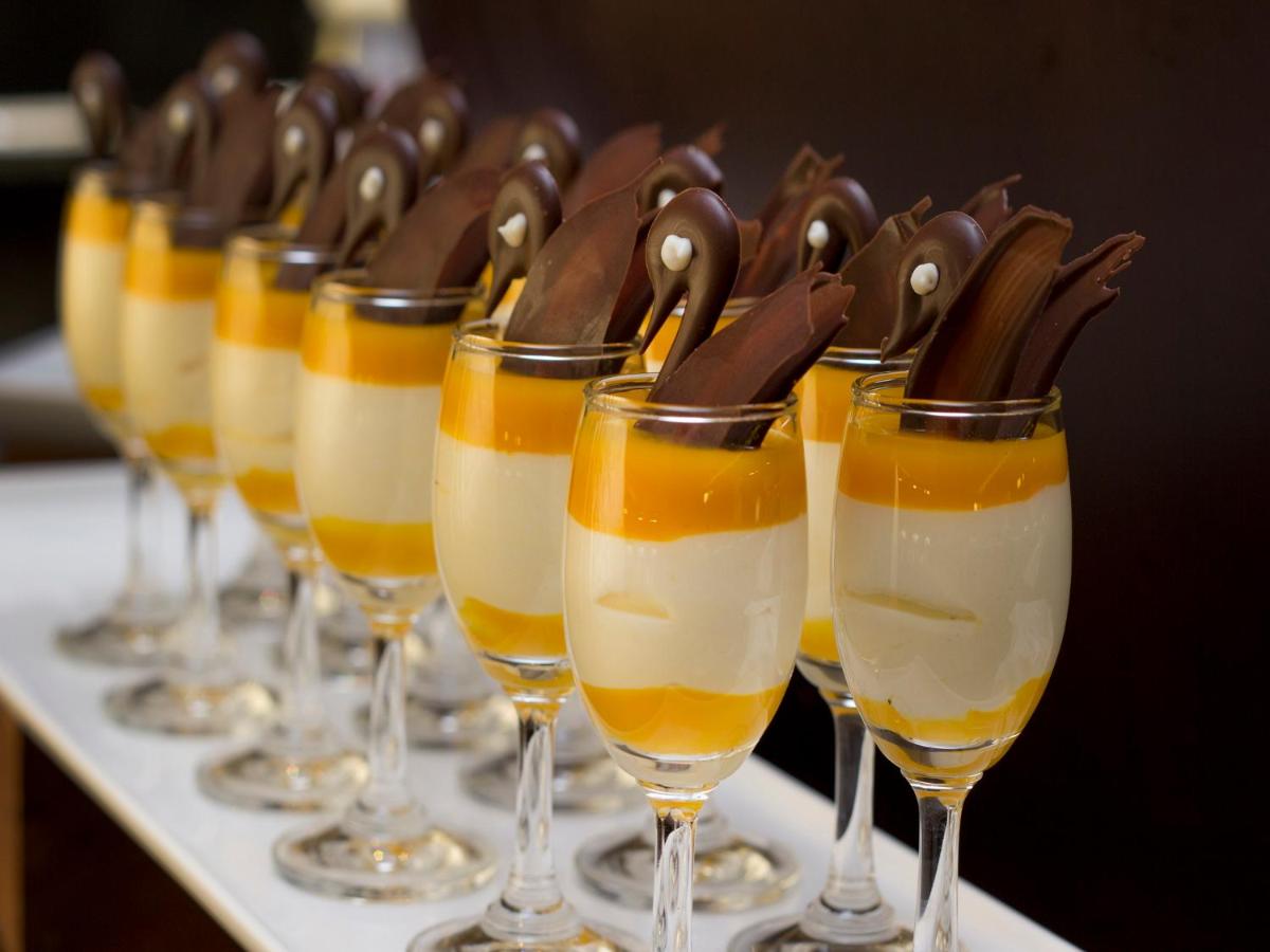 a row of wine glasses filled with desserts at Sterlings Mac Hotel in Bengaluru