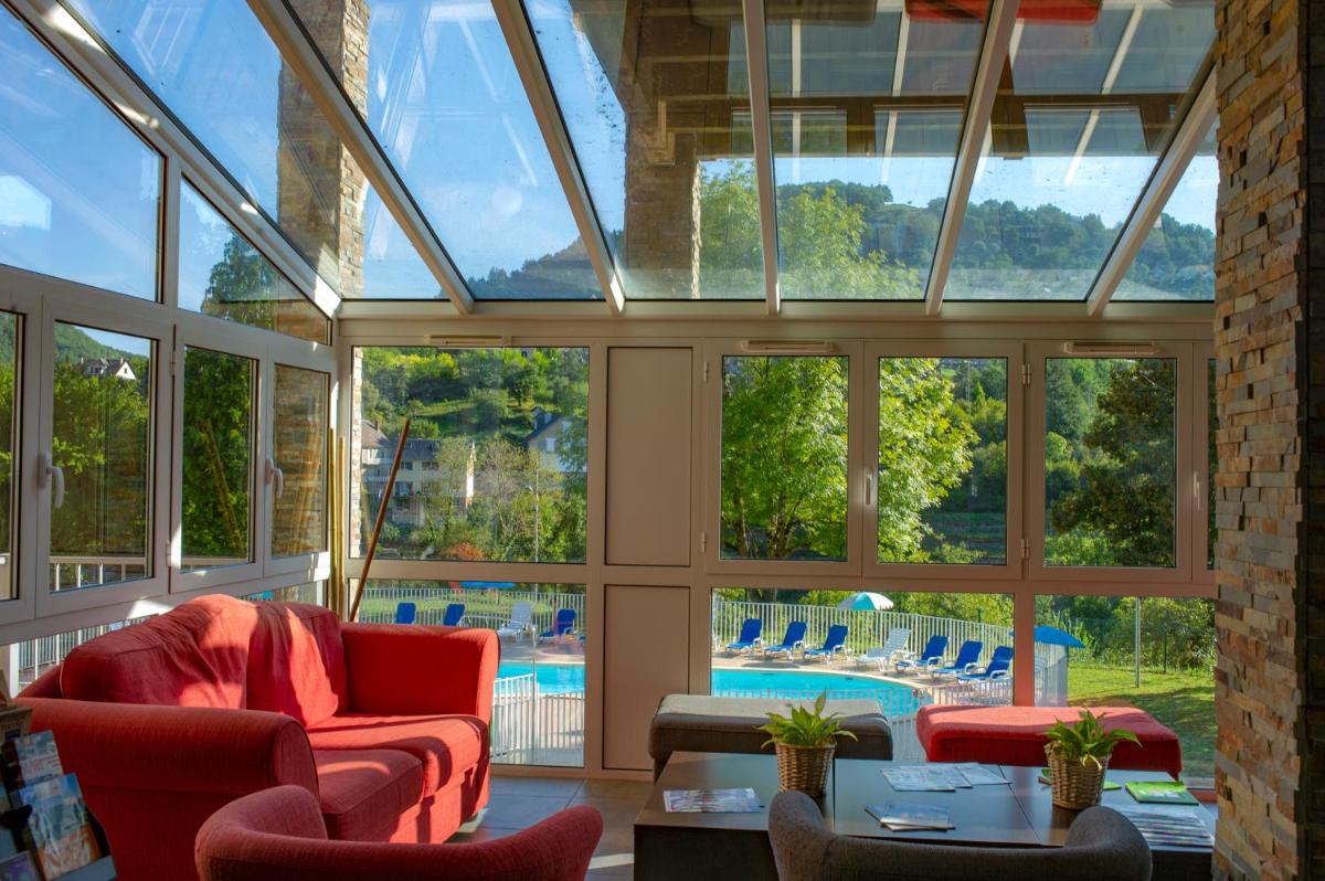 - un salon vide avec des fenêtres et une piscine dans l'établissement Résidence Goélia Les Gorges de la Truyère, à Entraygues-sur-Truyère