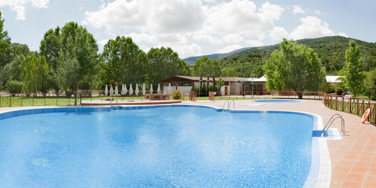 Una gran piscina azul con montañas al fondo. en Hotel Balneario Valle del Jerte, en Valdastillas
