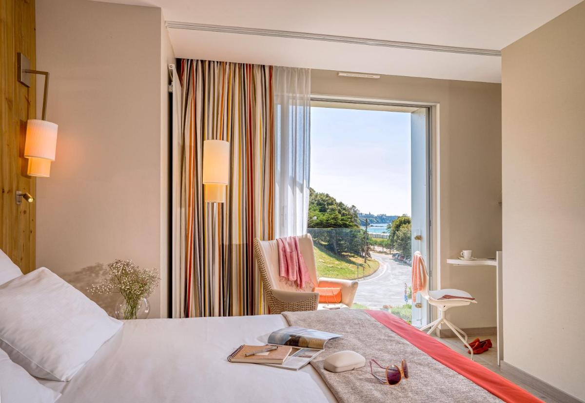 une chambre d'hôtel avec un lit et une grande fenêtre dans l'établissement Hôtel de la Baie - Thalassothérapie PREVITHAL, à Donville-les-Bains 25 autres photos