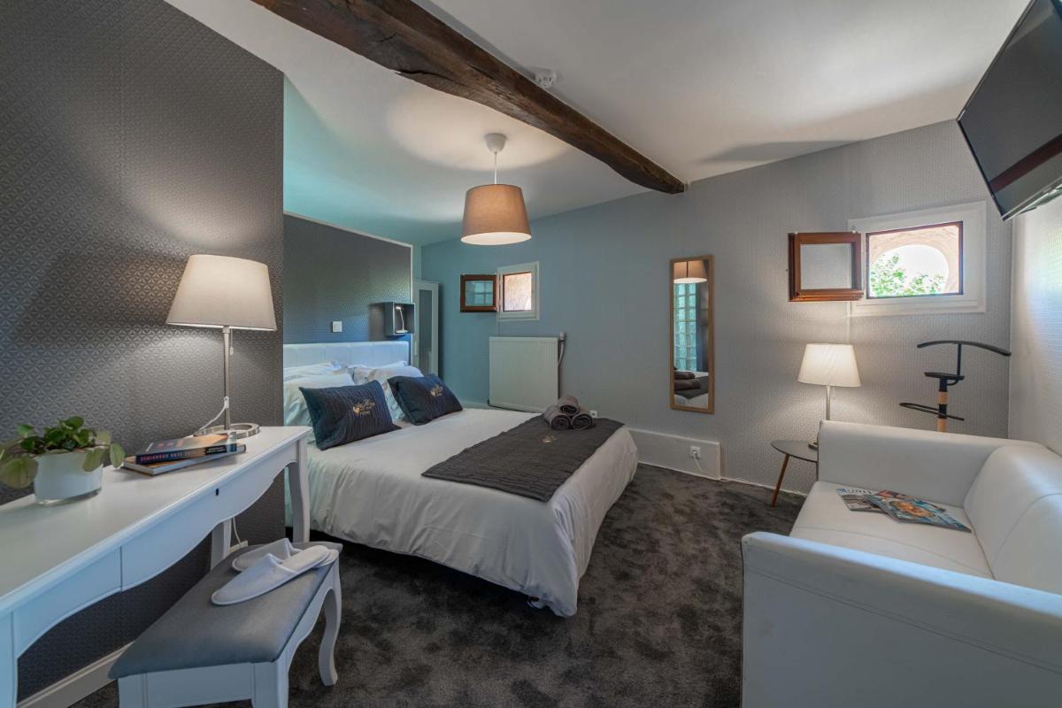 une chambre avec un lit, un bureau et un canapé dans l'établissement Hôtel Au Coq Dort Spa, à Châtillon-sur-Chalaronne