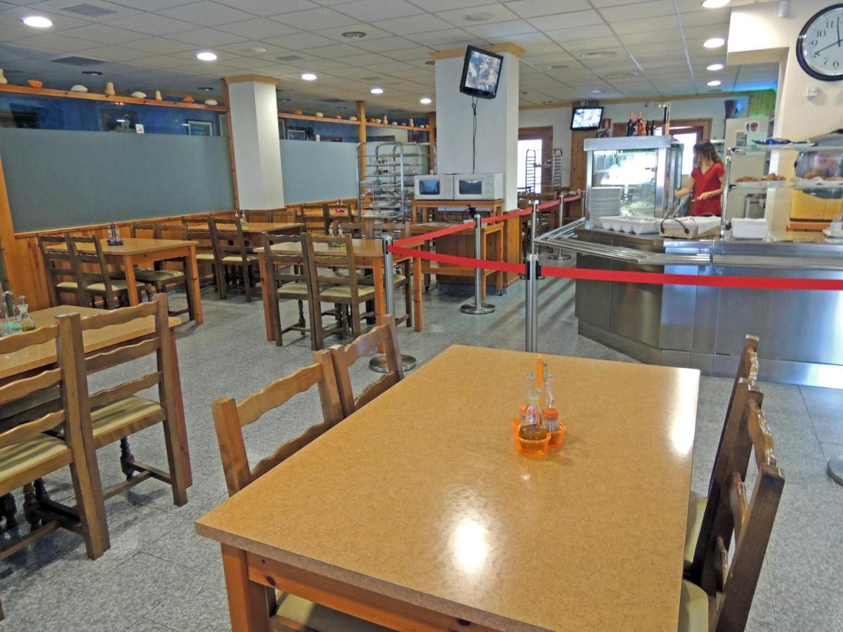 Un restaurante con mesas y sillas de madera y un mostrador. en Hotel Vilobi, en Vilobí d'Onyar