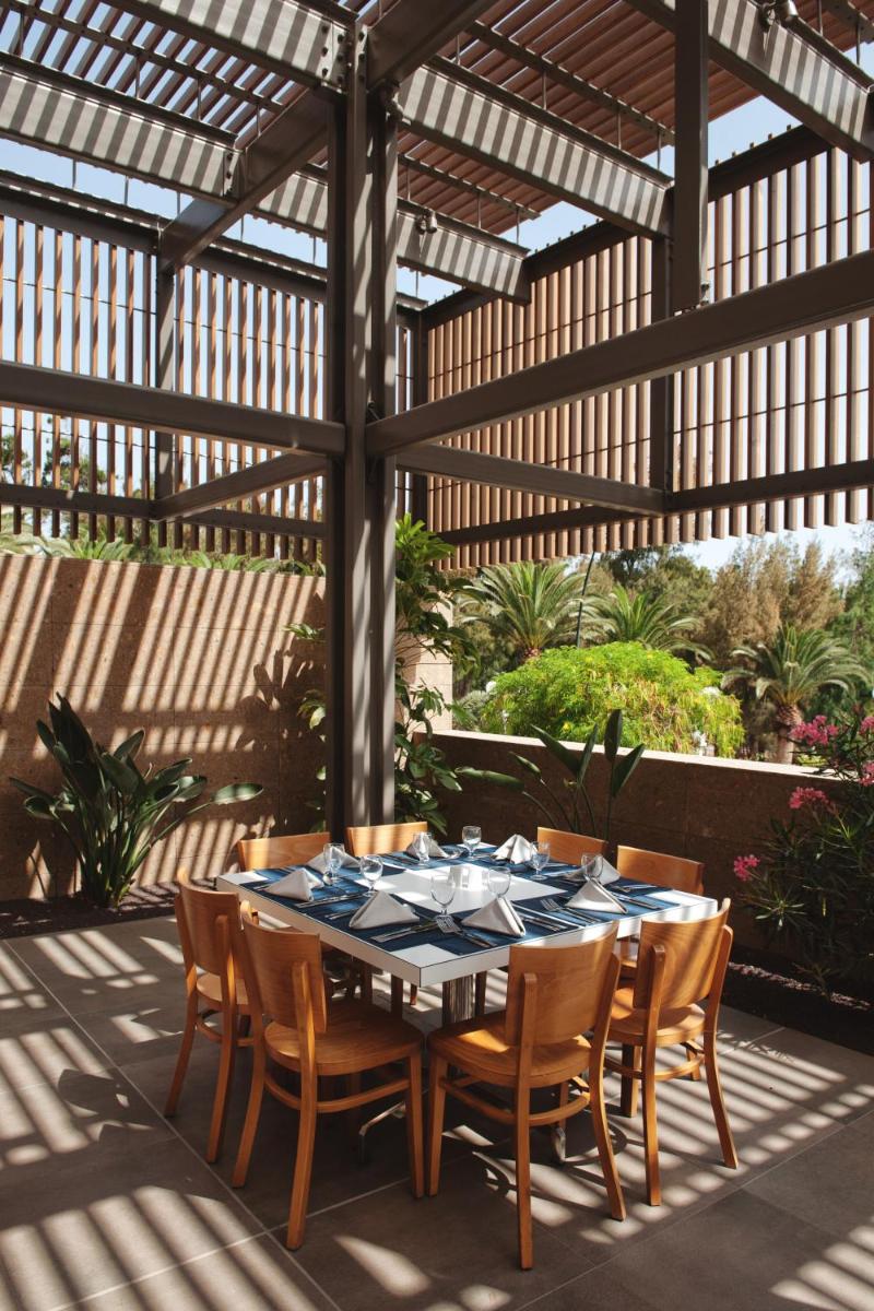 un patio con mesa y sillas bajo una pérgola en Sotavento Beach Club, en Costa Calma