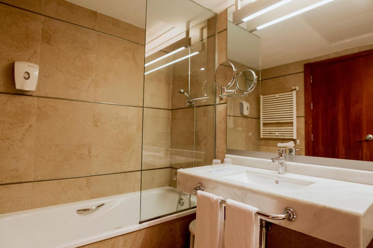 Un baño con lavabo, bañera y espejo. en Hotel Deloix 4* Sup, en Benidorm
