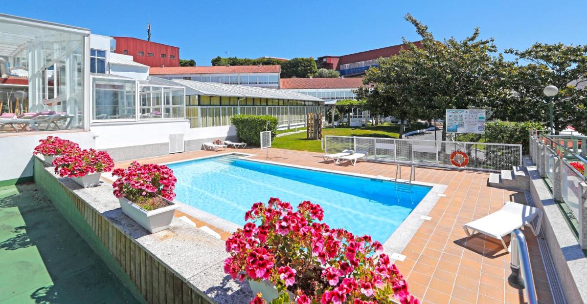 una piscina con flores en un edificio en Hotel Spa Congreso, en Teo