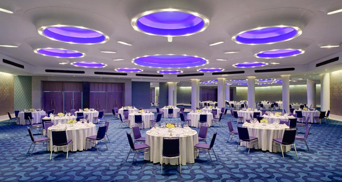 a banquet hall with white tables and chairs and blue lights at Avasa Hotel in Hyderabad