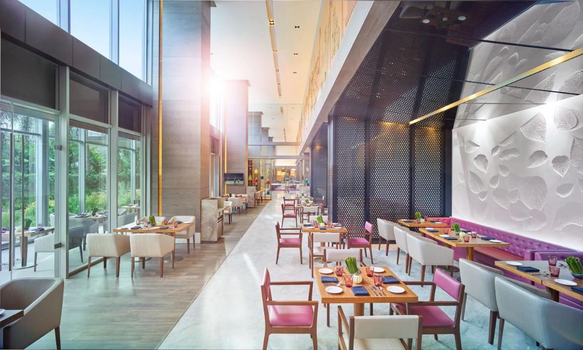 a restaurant with tables and chairs and windows at Vivanta Kolkata EM Bypass in Kolkata