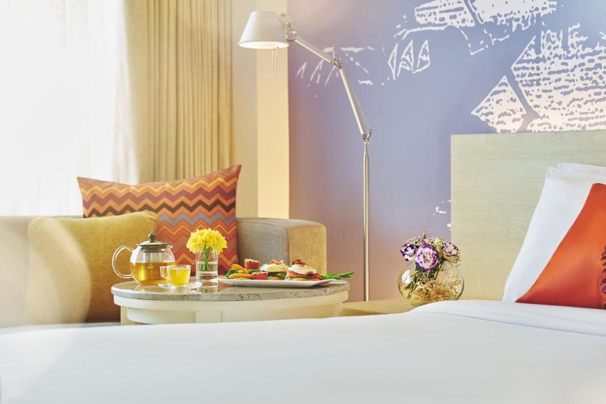 a hotel room with a bed and a table with food on it at Vivanta Kolkata EM Bypass in Kolkata