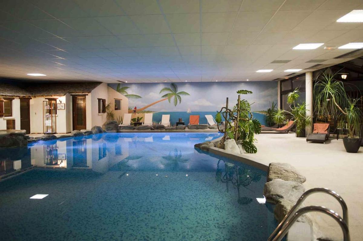 une grande piscine avec de l'eau bleue dans un immeuble dans l'établissement Auberge Du Camp Romain, à Chassey-le-Camp