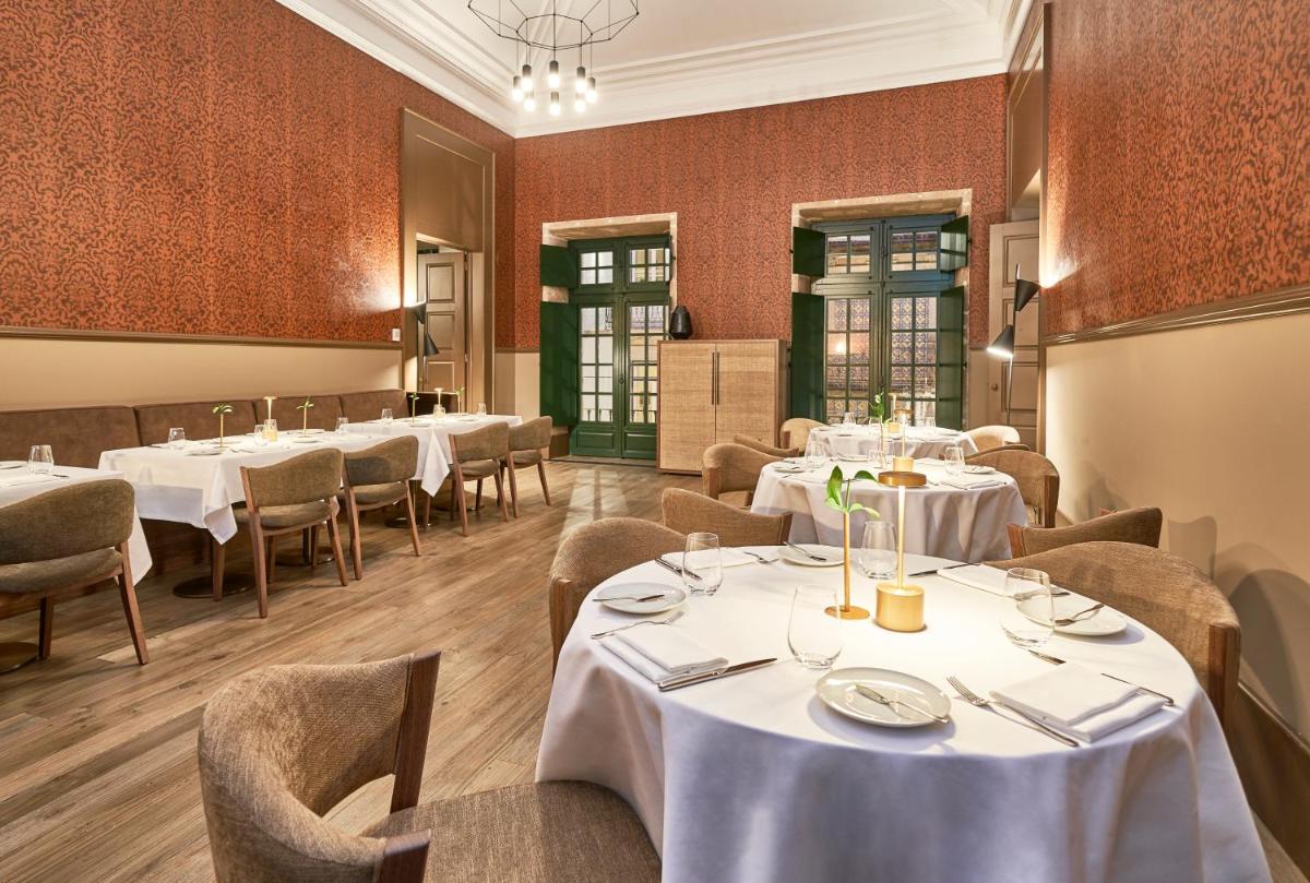 uma sala de jantar com mesas e cadeiras brancas em PortoBay Flores no Porto