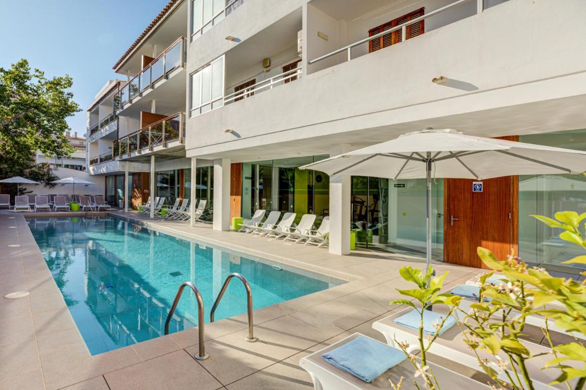 Una piscina con una sombrilla al lado de un edificio. en Hotel Miramar Mallorca, en Puerto Pollensa