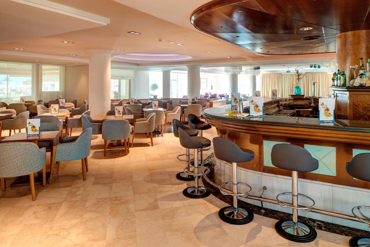 Un restaurante con barra, mesas y sillas. en Hipotels Hipocampo Playa, en Cala Millor