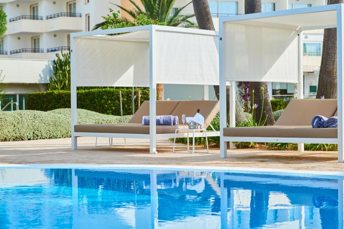 una piscina con 2 tumbonas junto a una piscina en Hipotels Said, en Cala Millor