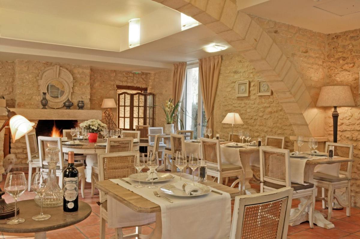 une salle à manger avec tables et chaises et une cheminée dans l'établissement Le Moulin de Mitou, à Auriac-du-Périgord