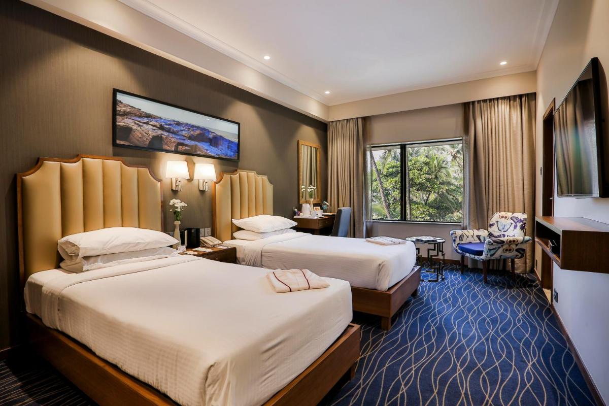a hotel room with two beds and a desk at Sun-n-Sand Mumbai Juhu Beach in Mumbai