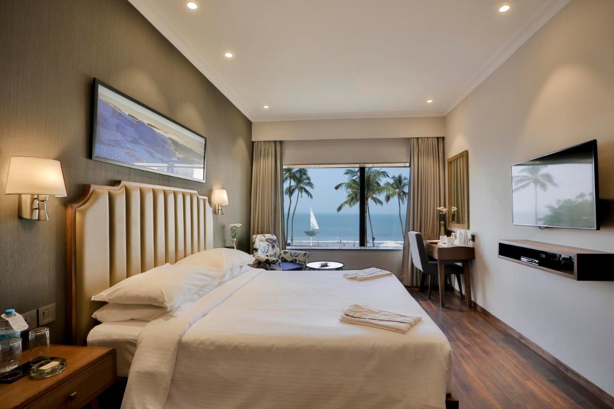 a hotel room with a bed and a desk and a window at Sun-n-Sand Mumbai Juhu Beach in Mumbai a hotel room with a bed and a desk and a window at Sun-n-Sand Mumbai Juhu Beach in Mumbai