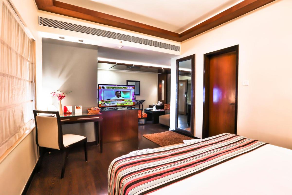 a hotel room with a bed and a desk and a television at Sun-n-Sand Mumbai Juhu Beach in Mumbai