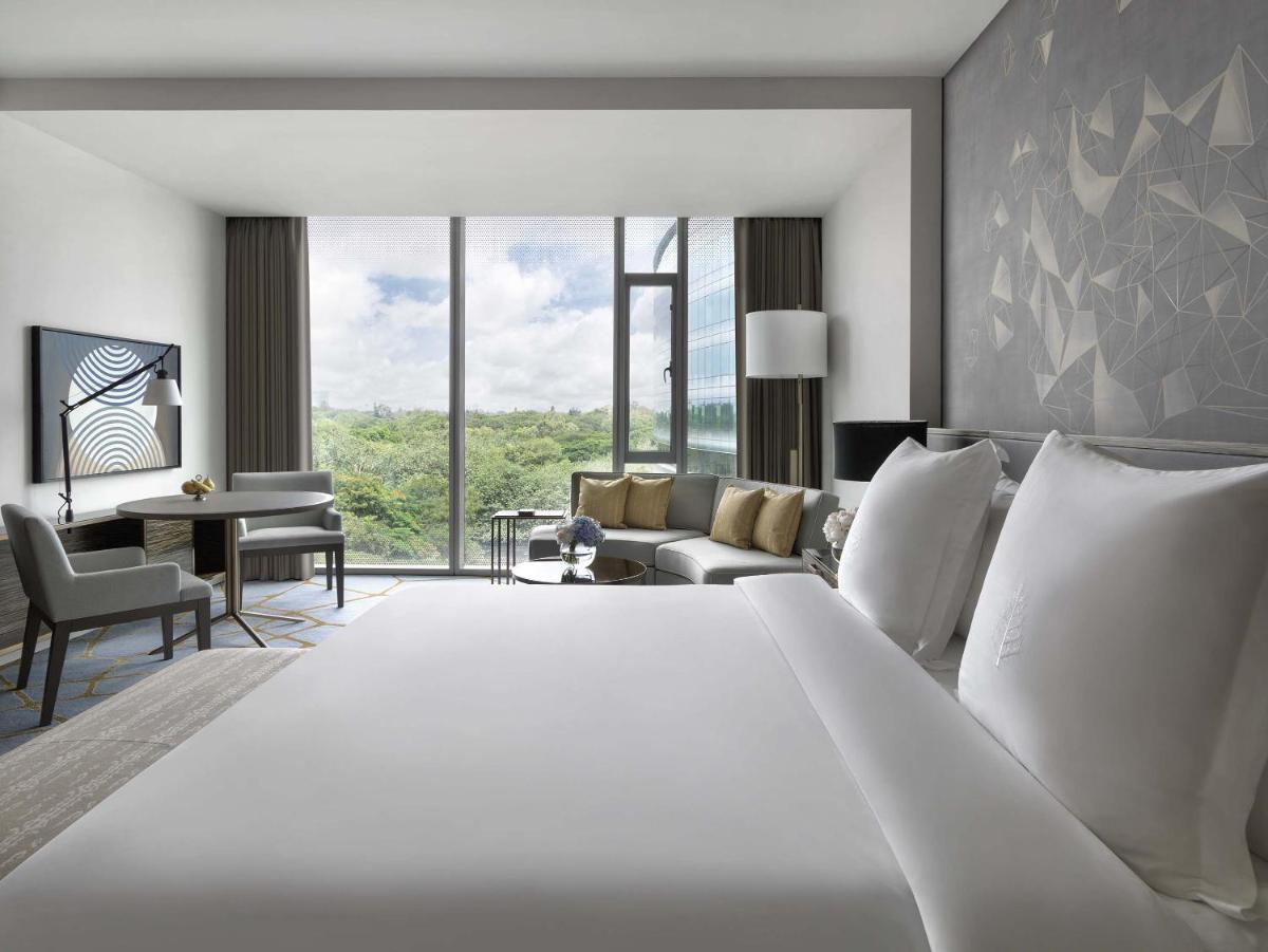 a bedroom with a large white bed and a living room at Four Seasons Hotel Bengaluru at Embassy ONE in Bengaluru a bedroom with a large white bed and a living room at Four Seasons Hotel Bengaluru at Embassy ONE in Bengaluru