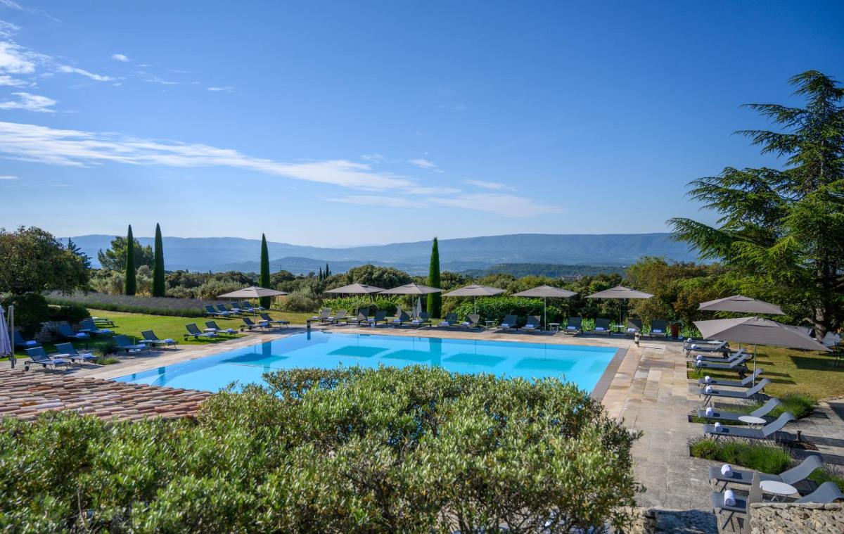 une grande piscine avec chaises longues et parasols dans l'établissement Hotel Les Bories & Spa, à Gordes