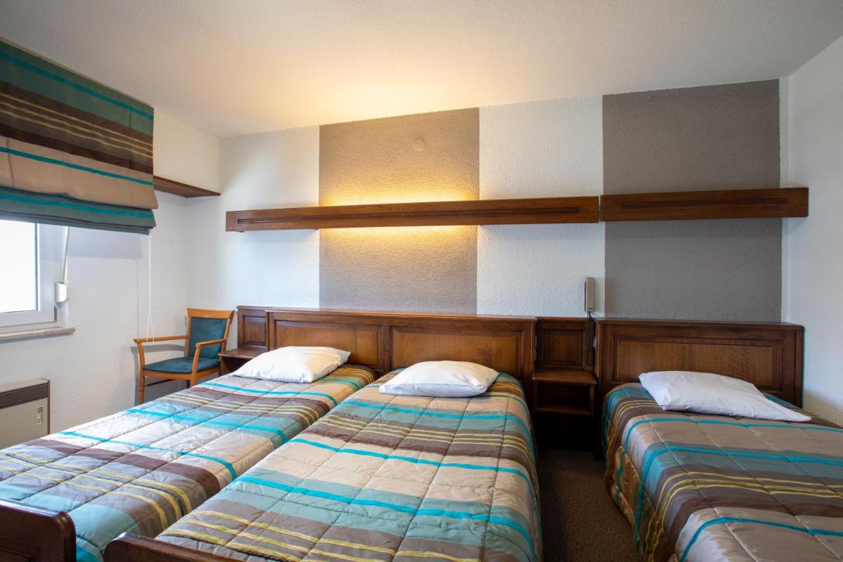 une chambre avec deux lits dans une pièce dans l'établissement Hôtel Restaurant et Spa Au Tilleul, à Labaroche 51 autres photos