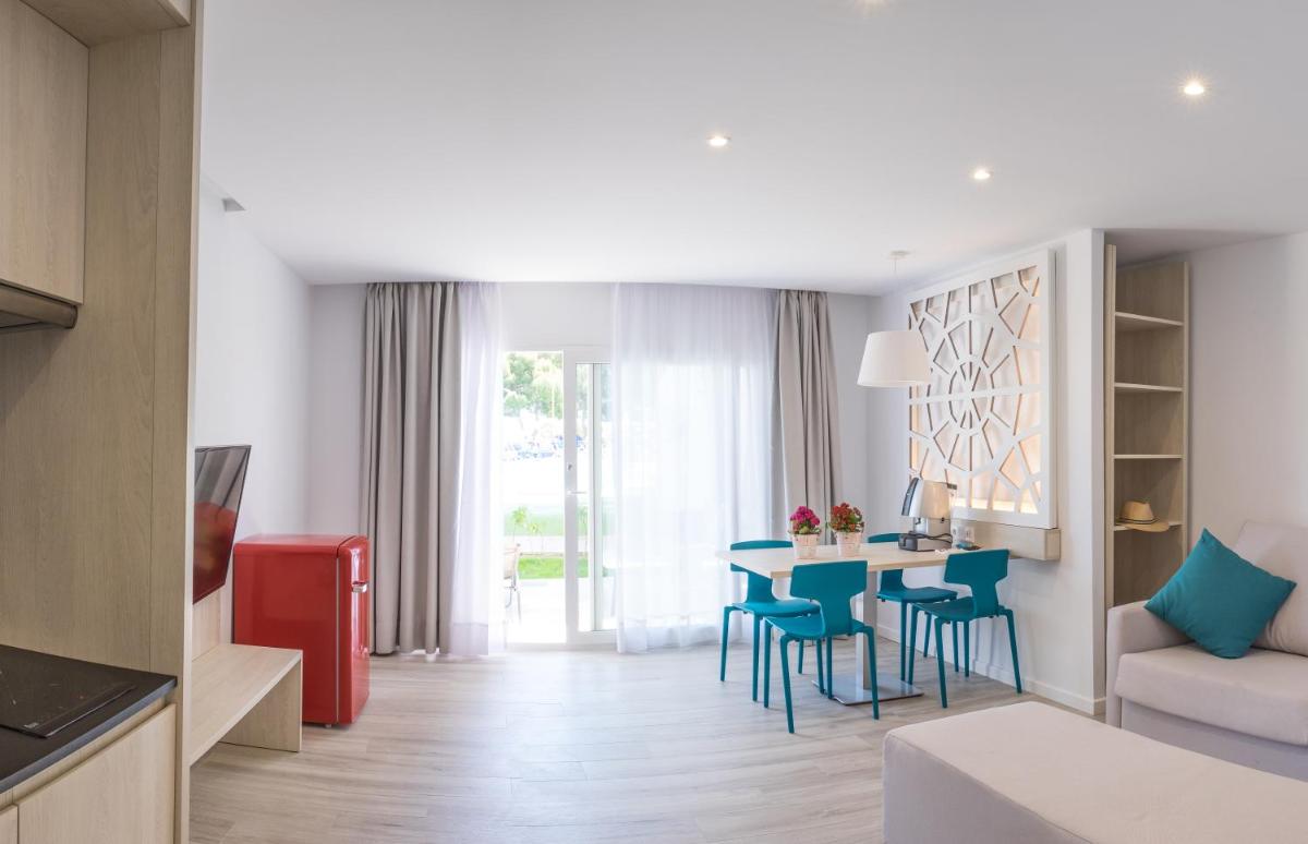 Una sala de estar con una mesa y sillas azules. en Hotel Club Es Talaial, en Cala d´Or