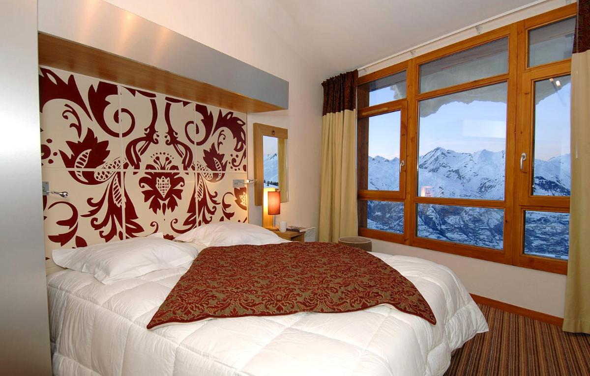 une chambre avec un grand lit et une fenêtre dans l'établissement Résidence Prestige Odalys Edenarc, à Arc 1800