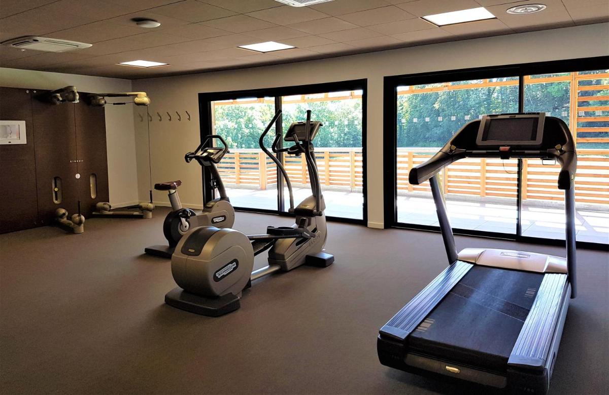 une salle de sport avec tapis de course et vélos elliptiques dans une pièce avec fenêtres dans l'établissement Mildiss Hotel Spa & Restaurant, BW Signature Collection, à Besse-et-Saint-Anastaise