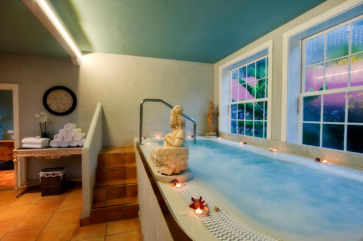 una gran piscina con una mujer sentada en una bañera en Hotel Hacienda de Abajo-Adults Only-Lujo, en Tazacorte