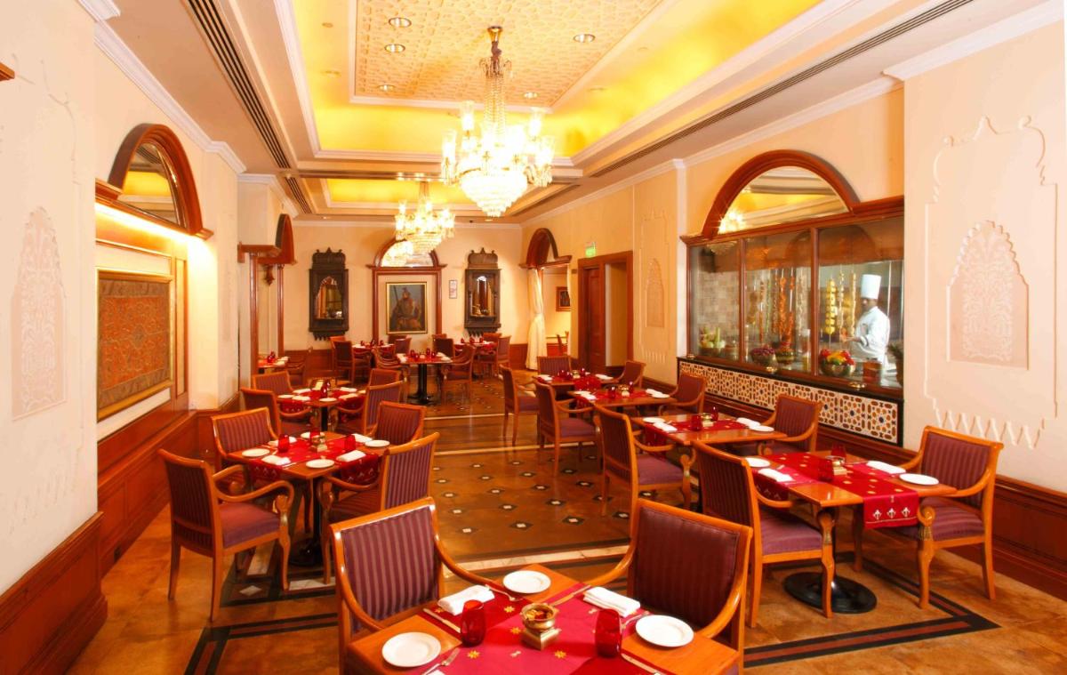 a restaurant with tables and chairs and a chandelier at Eros Hotel New Delhi, Nehru Place in New Delhi a restaurant with tables and chairs and a chandelier at Eros Hotel New Delhi, Nehru Place in New Delhi