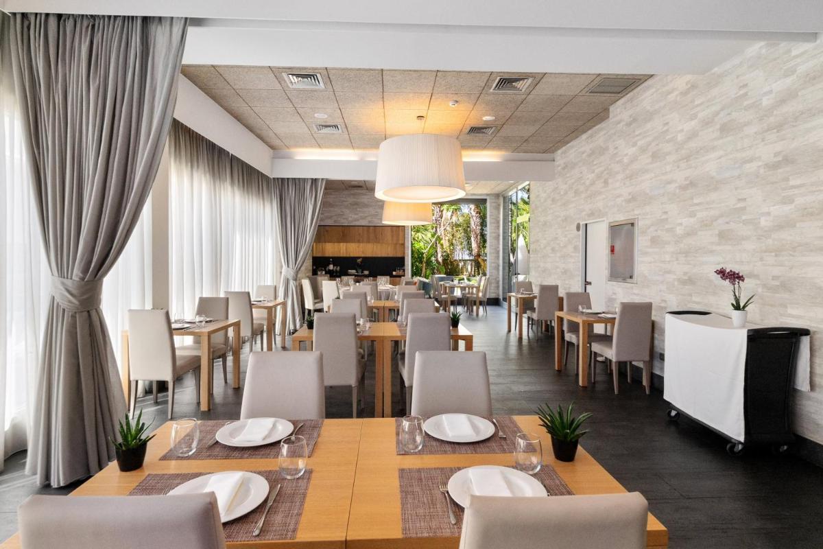 un restaurante con mesas y sillas de madera y una pared de piedra. en Hotel Areca, en Torrellano