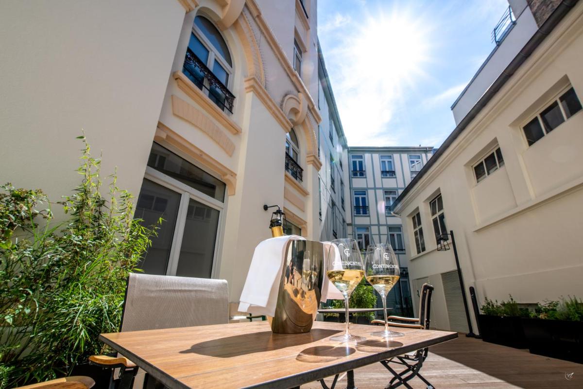 - une table avec deux verres de vin sur le balcon dans l'établissement Continental Hotel, à Reims