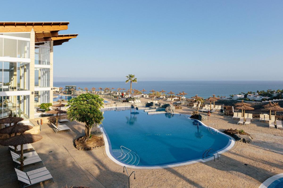 Una gran piscina junto a un edificio y el océano. en Alua Village Fuerteventura - All Inclusive, en Playa de Jandía