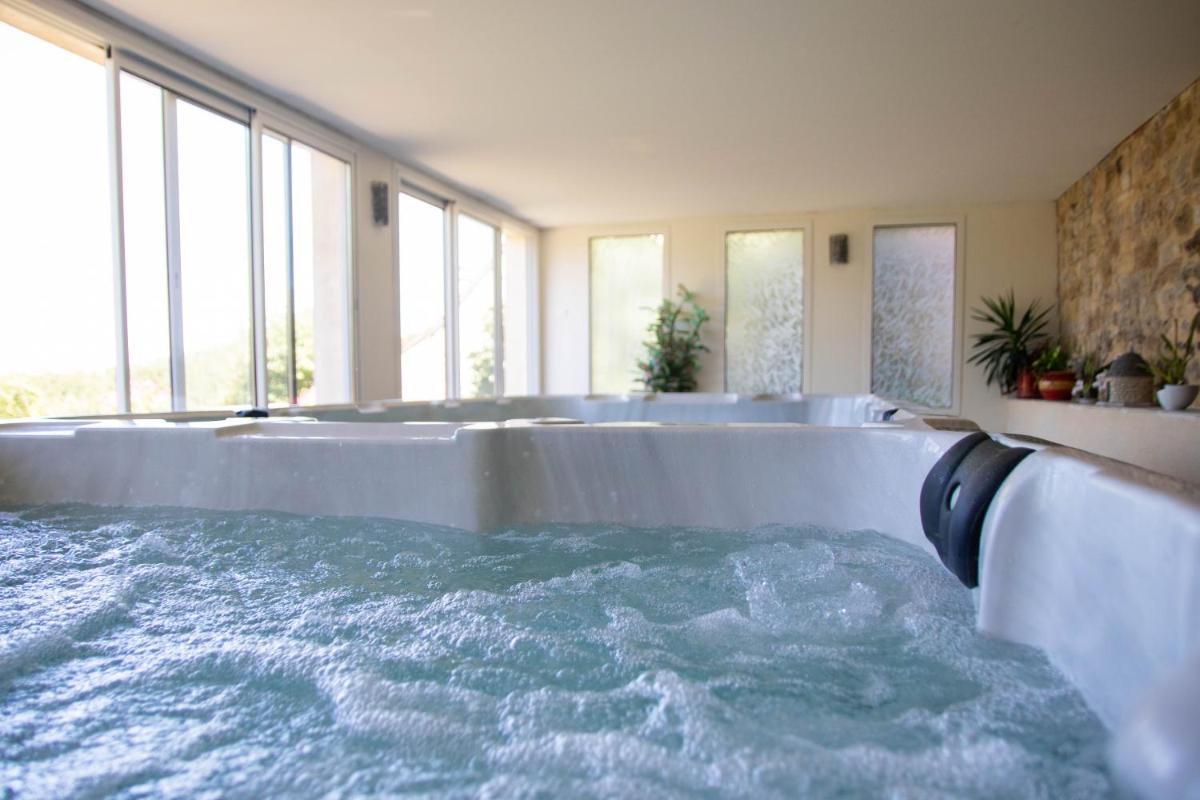 La salle de bains est pourvue d'une grande baignoire remplie d'eau. dans l'établissement Domaine de Janis & Spa, au Vigan
