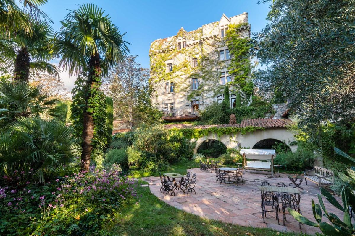 un jardin avec des tables et des chaises en face d'un bâtiment dans l'établissement Château De Riell, à Molitg-les-Bains