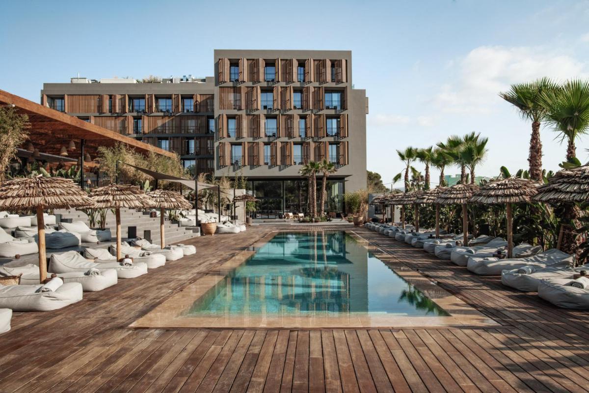 un complejo con piscina y palmeras en OKU Ibiza, en San Antonio