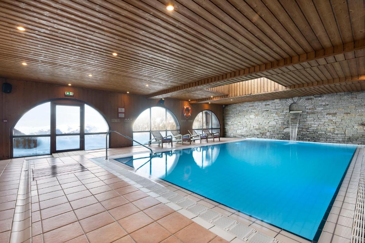 - une grande piscine dans une grande pièce dotée d'une grande fenêtre dans l'établissement Hôtel Les Balcons Village, à Belle Plagne