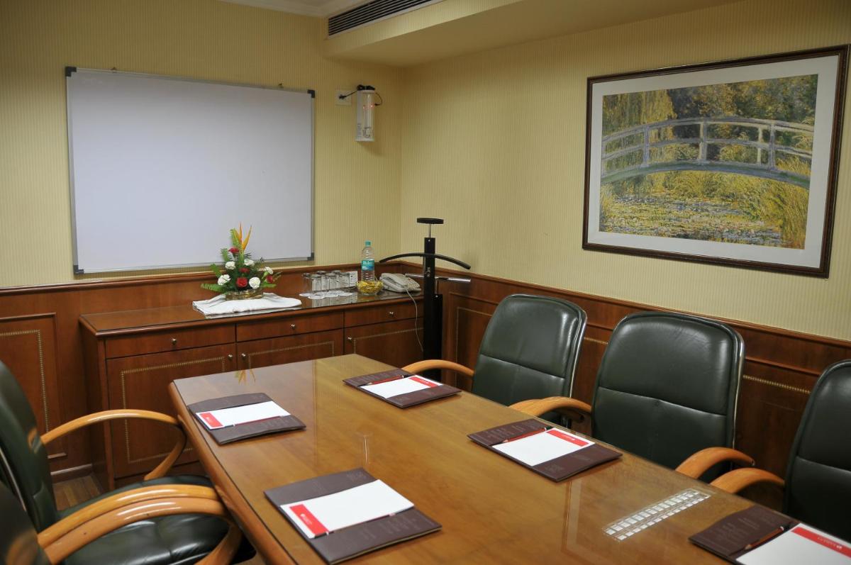 a meeting room with a table and chairs and a whiteboard at Ramada Plaza By Wyndham Palm Grove in Mumbai