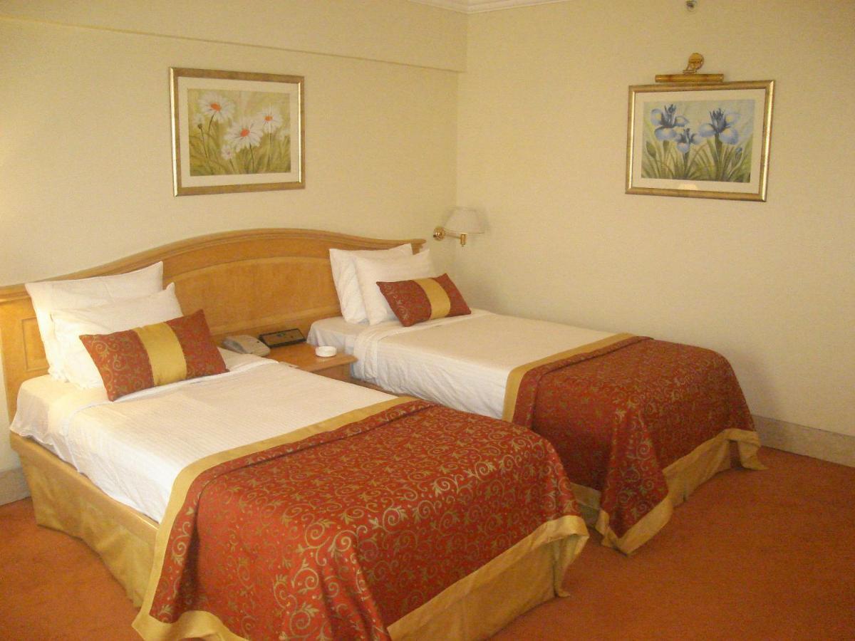 a hotel room with two beds in a room at Ramada Plaza By Wyndham Palm Grove in Mumbai