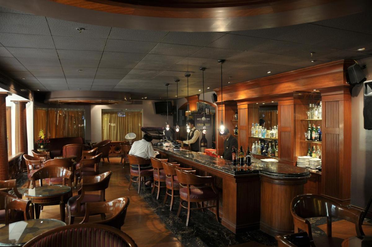 a bar in a restaurant with tables and chairs at Ramada Plaza By Wyndham Palm Grove in Mumbai