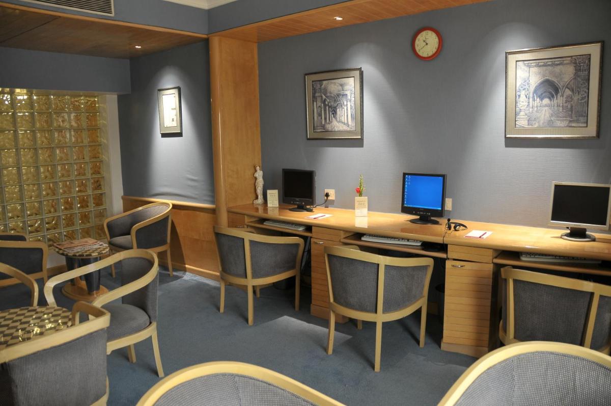 a waiting room with a desk with two monitors and chairs at Ramada Plaza By Wyndham Palm Grove in Mumbai