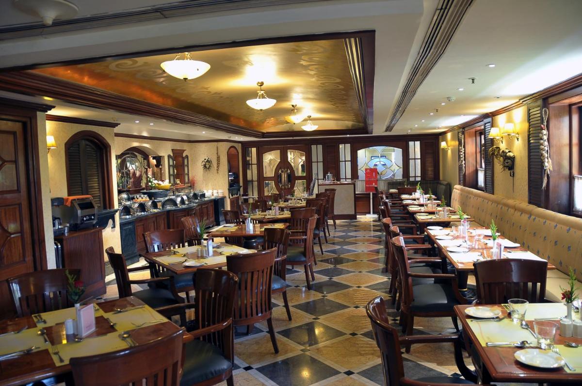 a restaurant with wooden tables and chairs in a room at Ramada Plaza By Wyndham Palm Grove in Mumbai