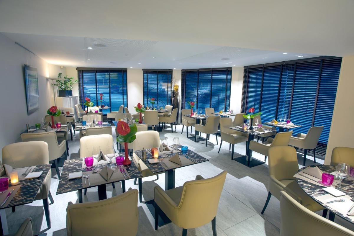 une salle à manger avec tables, chaises et fenêtres dans l'établissement Eden Hotel & Spa, à Cannes